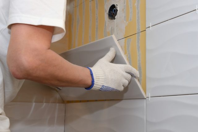 construction work laying tile on the wall close up